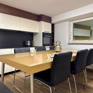 a dining room with a wooden table and chairs at In The House Hostel in Prishtinë
