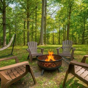 a fire pit with three chairs and a hammock at Renovated Cottage - Game Room - Fire Pit - Sleeps 8 in Moreland Hills
