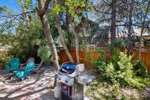a backyard with a grill and chairs and a fence at Charming Tiny Home in Boise's North End in Boise