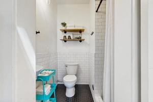 a white bathroom with a toilet and a shelf at Charming Tiny Home in Boise's North End in Boise +14 photos