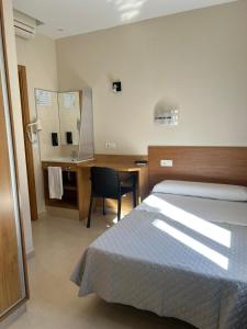 a bedroom with a bed and a desk with a chair at Hostal Costabella in Fuengirola