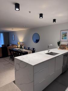 a kitchen with a sink and a living room at Beach Getaway in Mount Maunganui