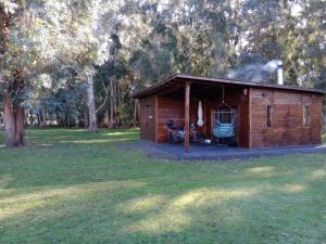 a small wooden cabin with a grill in a park at Cabañas La Mansa, Casa grande in Balcarce