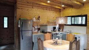 a kitchen with a refrigerator and a table in a cabin at Cabañas La Mansa, Casa grande in Balcarce