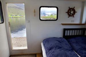 a bedroom with a bed and a window on a boat at Captains Room - Havborg in Hvannasund