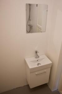a bathroom with a white sink and a mirror at Captains Room - Havborg in Hvannasund