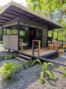 a small cabin with a deck in a garden at Glamping las palmas in Nimaima +3 photos