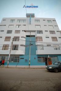 ein weiß-blaues Gebäude mit einem davor geparkten Auto in der Unterkunft Hotel JORGE CHAVEZ in Trujillo