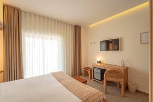 een hotelkamer met een bed, een bureau en een televisie bij Authentic Tavira Hotel in Tavira
