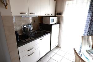 a small kitchen with a sink and a microwave at Czanek Apartman in Komárom