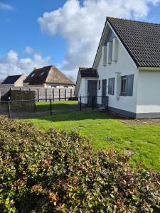 a white house with a fence in a yard at vacation home 68 in Tzummarum