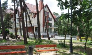 two benches in a park in front of a building at Apartament Morska Ostoja in Krynica Morska