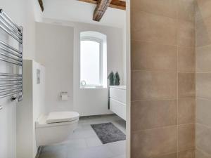 a white bathroom with a toilet and a window at Two-Story Loft with Large Terrace in Løkken +10 photos
