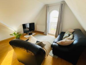 a living room with a black leather couch and a television at Giebelglück - 3 Zimmer, direkt an der UniKlinik, 2 Schlafzimmer, 4 Gäste, WLAN in Würzburg