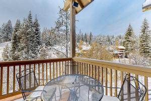 a balcony with a table and chairs and snow covered trees at Need for Speed in Donnelly
