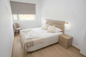 a bedroom with a bed and a chair and a window at Apartamentos Turísticos El Cholo in Fisterra