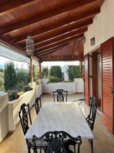 a table and chairs on a patio with a wooden ceiling at Fokiotrypa Seaside Retreat in Marathias