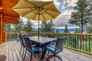 a table and chairs on a deck with an umbrella at Cascade Lakeview Log Cabin in Cascade