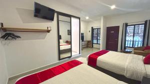 a bedroom with two beds and a tv on the wall at HOTEL SOÍ BACALAR in Bacalar