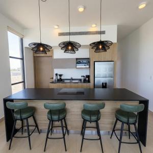 a kitchen with a black island with green bar stools at Kocoy Oceanfront condo in Punta Peninsula in Bahía Kino