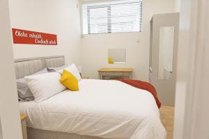 a bedroom with a white bed with yellow pillows at Derry City Centre 1 & 2 Bedroom Modern Apartments in Derry Londonderry