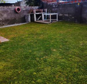 a yard with a green lawn with a red hose at Martin House in Chascomús