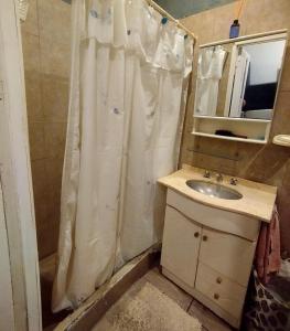 a bathroom with a shower curtain and a sink at Martin House in Chascomús