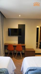 a hotel room with two beds and a desk with a flat screen tv at Nexus Conceição in São Paulo