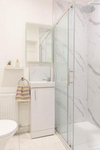 a white bathroom with a glass shower stall at Derry City Centre 1 & 2 Bedroom Modern Apartments in Derry Londonderry +61 photos