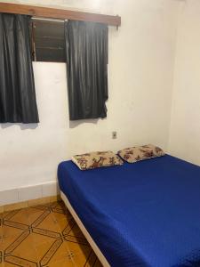 a bedroom with a bed with blue sheets and a window at Casa 3 Quartos Espaço Luxemburgo in Anápolis
