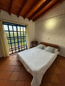 a bedroom with a bed and a large window at Finca Cercanías Marinilla - Casa Campestre in Marinilla