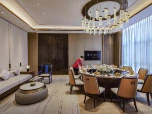 a woman standing in a living room with a dining room at Pullman Yueyang in Yueyang