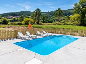 a swimming pool with chairs and a fence at Apartamentos Turísticos El Cholo in Fisterra