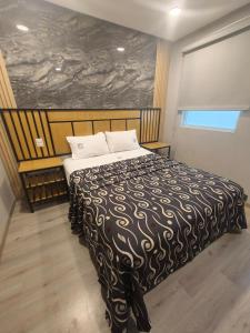 a bedroom with a bed with a black and white blanket at Hotel Torreon in Mexico City