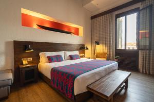 a bedroom with a large bed with a bench in it at Sophia Hotel By OxoHotel in Cartagena de Indias