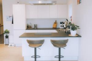 a kitchen with white cabinets and two bar stools at High end 3 BR Spacious Villa for 6 guests in Norðskáli