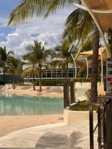 a swimming pool with palm trees and a building at Cloud Haven Suite at Azure North Pampanga in San Fernando