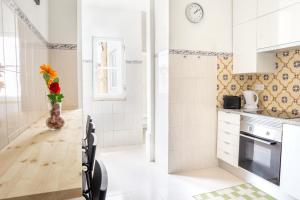 a white kitchen with a vase of flowers on a table at Bica Palace - Residence in Center of Lisbon in Lisbon