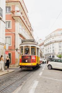a yellow and red tram on a city street at Bica Palace - Residence in Center of Lisbon in Lisbon