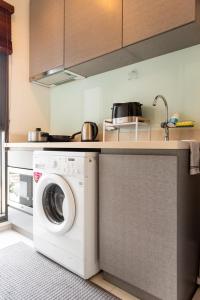a kitchen with a washing machine under a counter at Upscale Apartment With Train Access Bts Thonglor in Bangkok