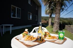 a table with sandwiches and french fries and a bottle of beer at Guest House Goofy in Hyuga