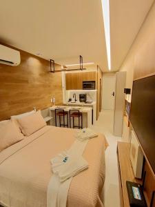 a bedroom with a large bed and a kitchen at Maré alta flat 213 in Tamandaré