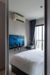 a bedroom with a bed and a tv and a window at Upscale Apartment With Train Access Bts Thonglor in Bangkok