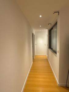 a hallway with white walls and wooden floors and a window at sony cottage in Lisbon