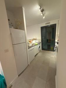 a white kitchen with a refrigerator and a dishwasher at sony cottage in Lisbon