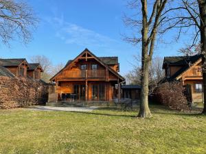 a large wooden house with a tree in the yard at Forest Villa, Rural Twente in Den Ham
