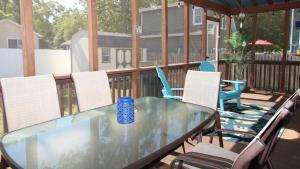 a glass table on a deck with chairs at Shell Shack in Villas