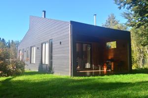 a black and gray house on a grass field at Rümü in Pucón