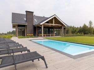 a house with a swimming pool and chairs at Villa with Heated Pool, Sauna in Aalten