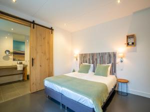 a bedroom with a large bed and a bathroom at Grand Villa with Sauna & Jacuzzi in Den Burg